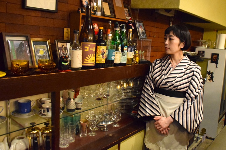 마음에 드는 식기나 소품이 장식된 선반 앞에서 고객에 대한 생각을 말하는 우츠키씨